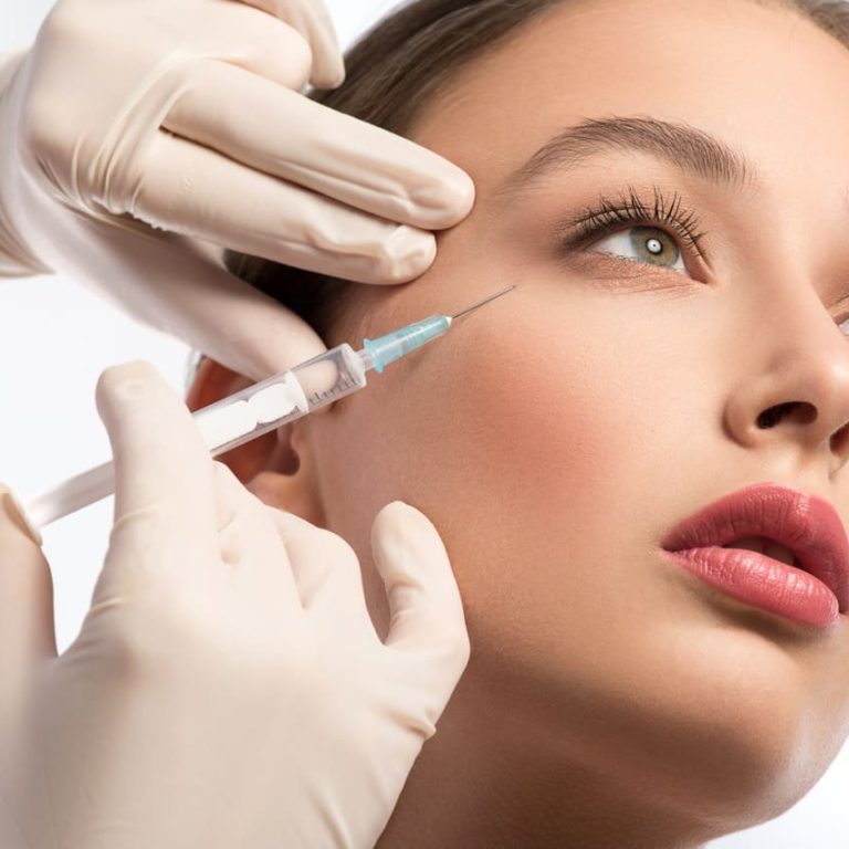 Serine young woman is getting facial botox injection. Beautician hands in gloves holding syringe near her face